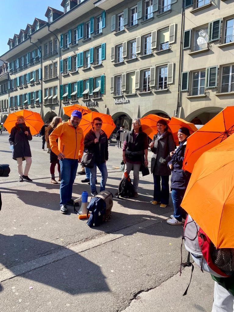 Verschiedene Personen mit orangen Procap Schirmen auf dem Waisenhausplatz